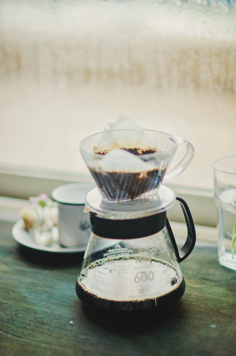 Glass pour-over coffee server with V60 dripper and coffee grounds.