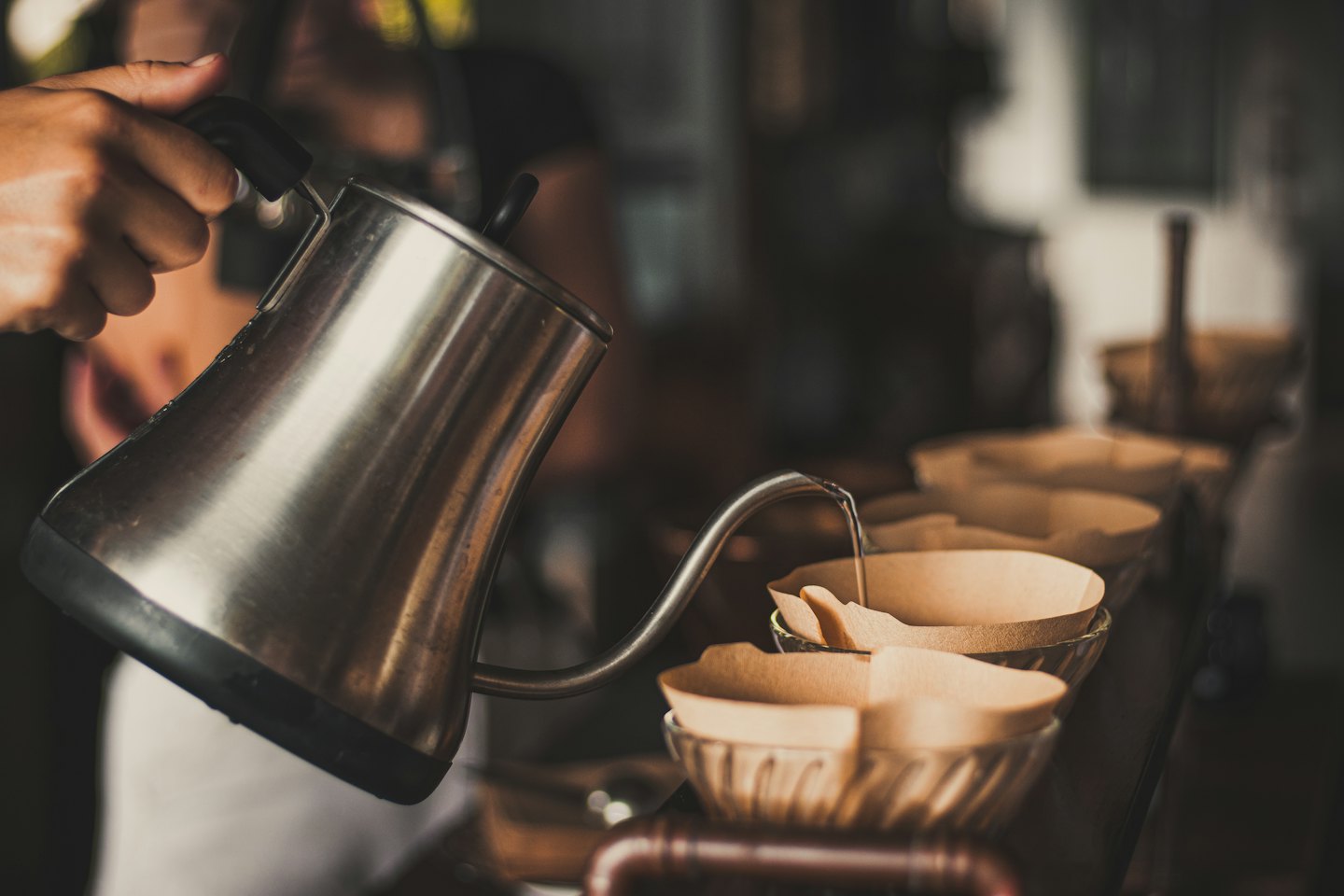 Barista pours hot water into pour-over coffee filters.