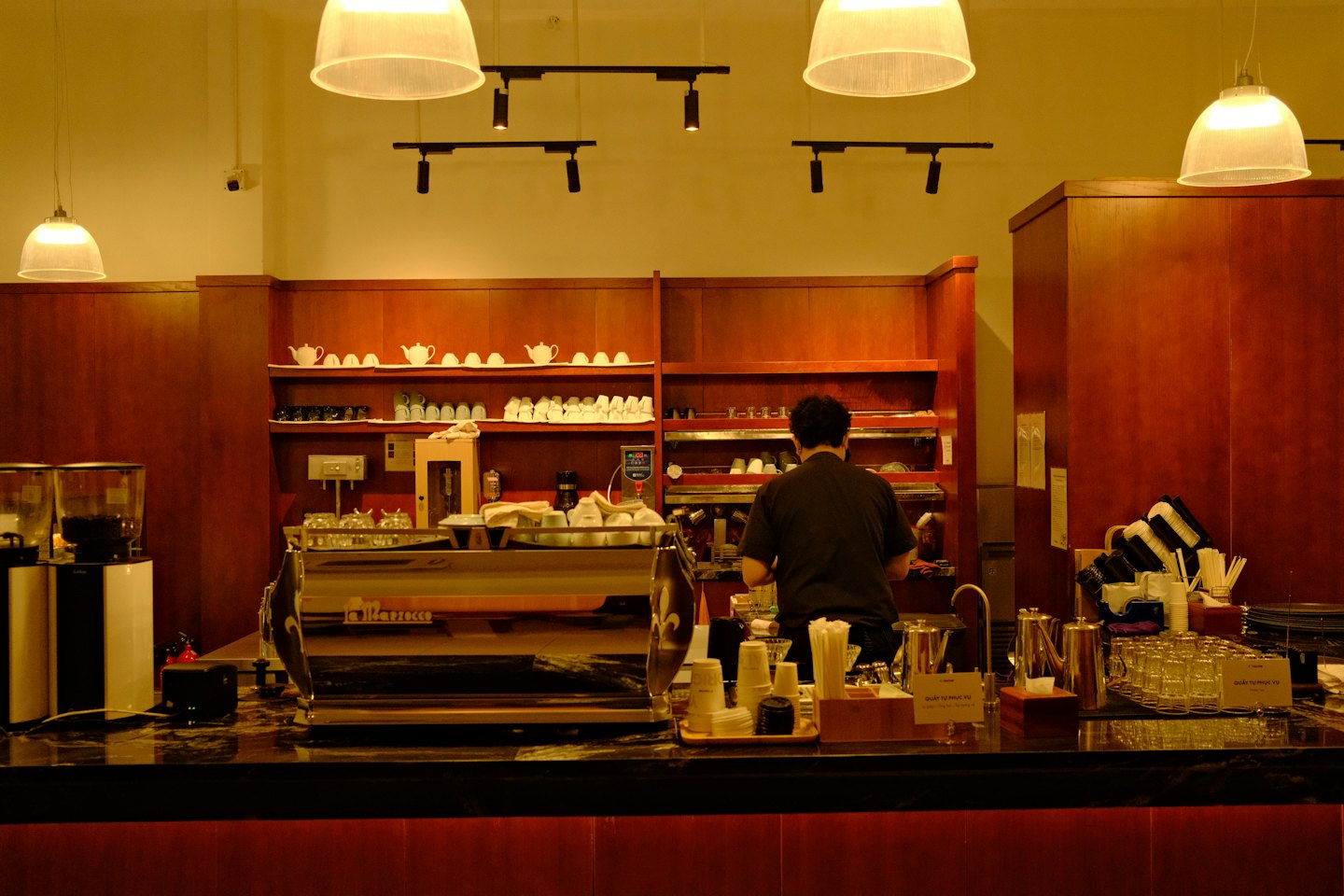 A barista prepares coffee at a modern marble counter.