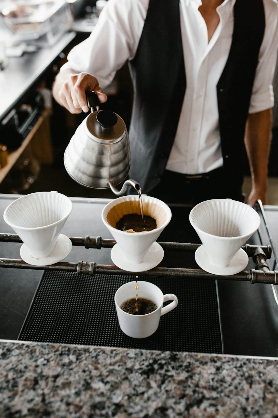 Barista carefully pours hot water for pour-over coffee.