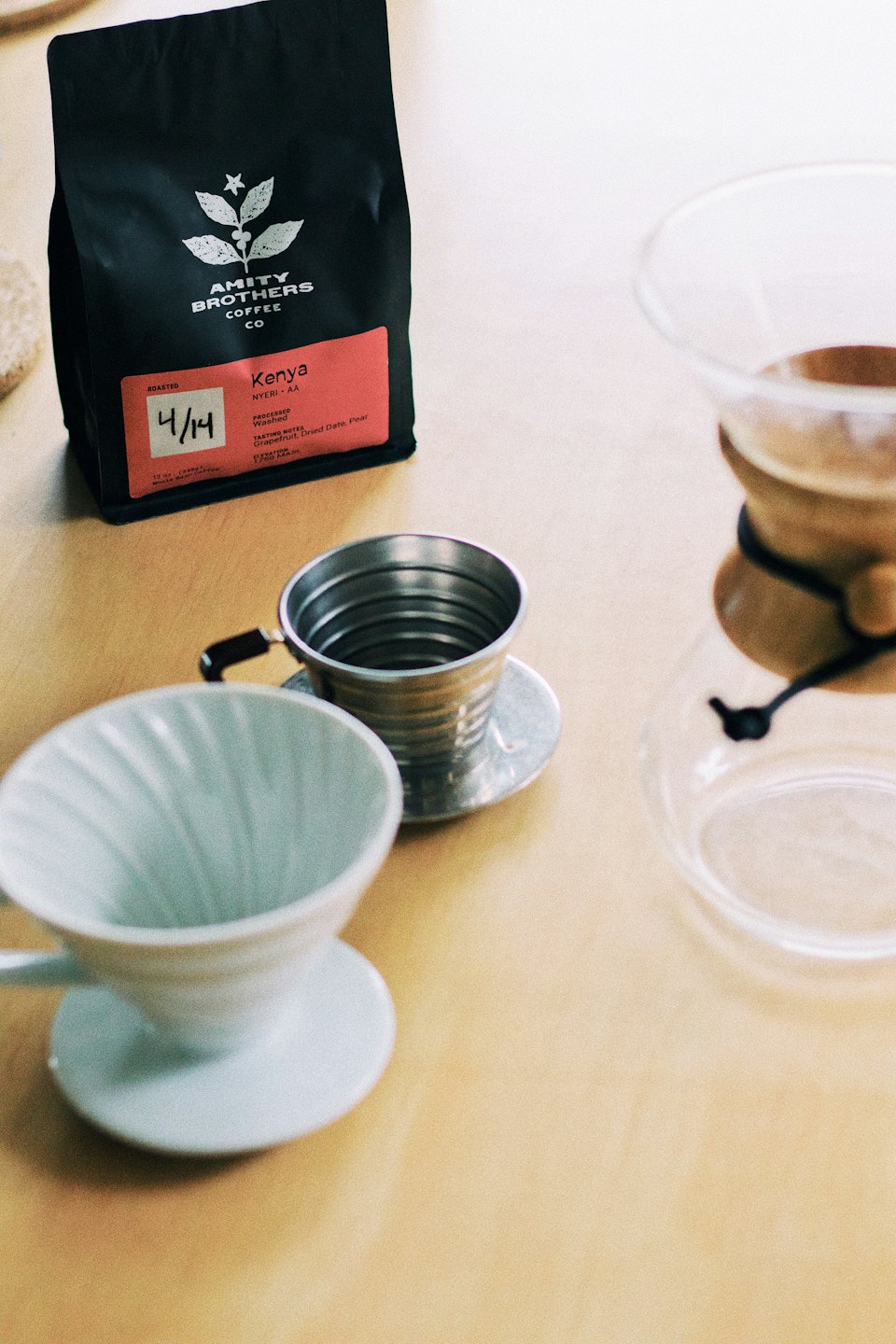 Coffee brewing supplies and coffee beans arranged on a wooden table.